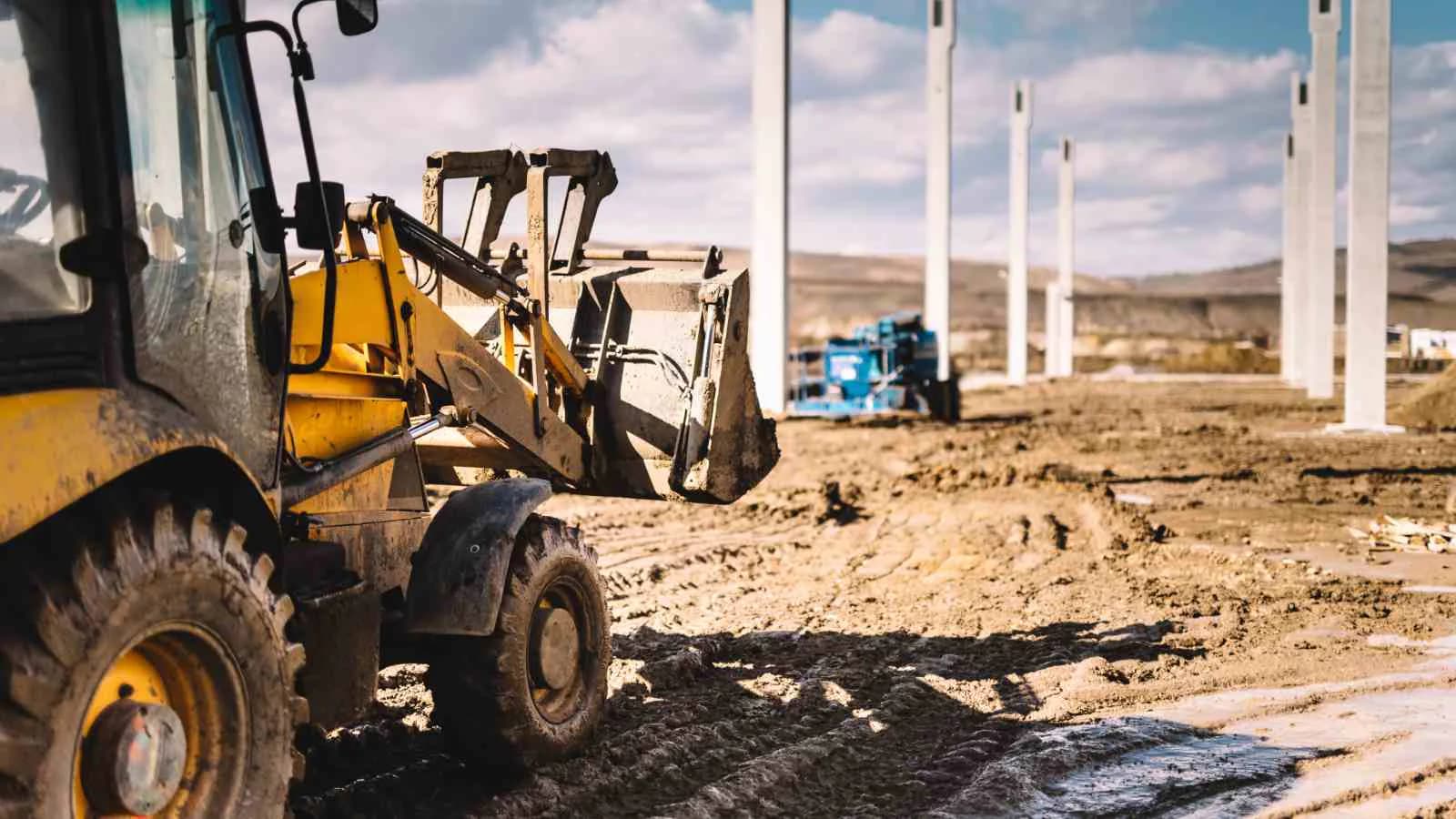 Maquinaria pesada trabajando en la construcción de una nave industrial.