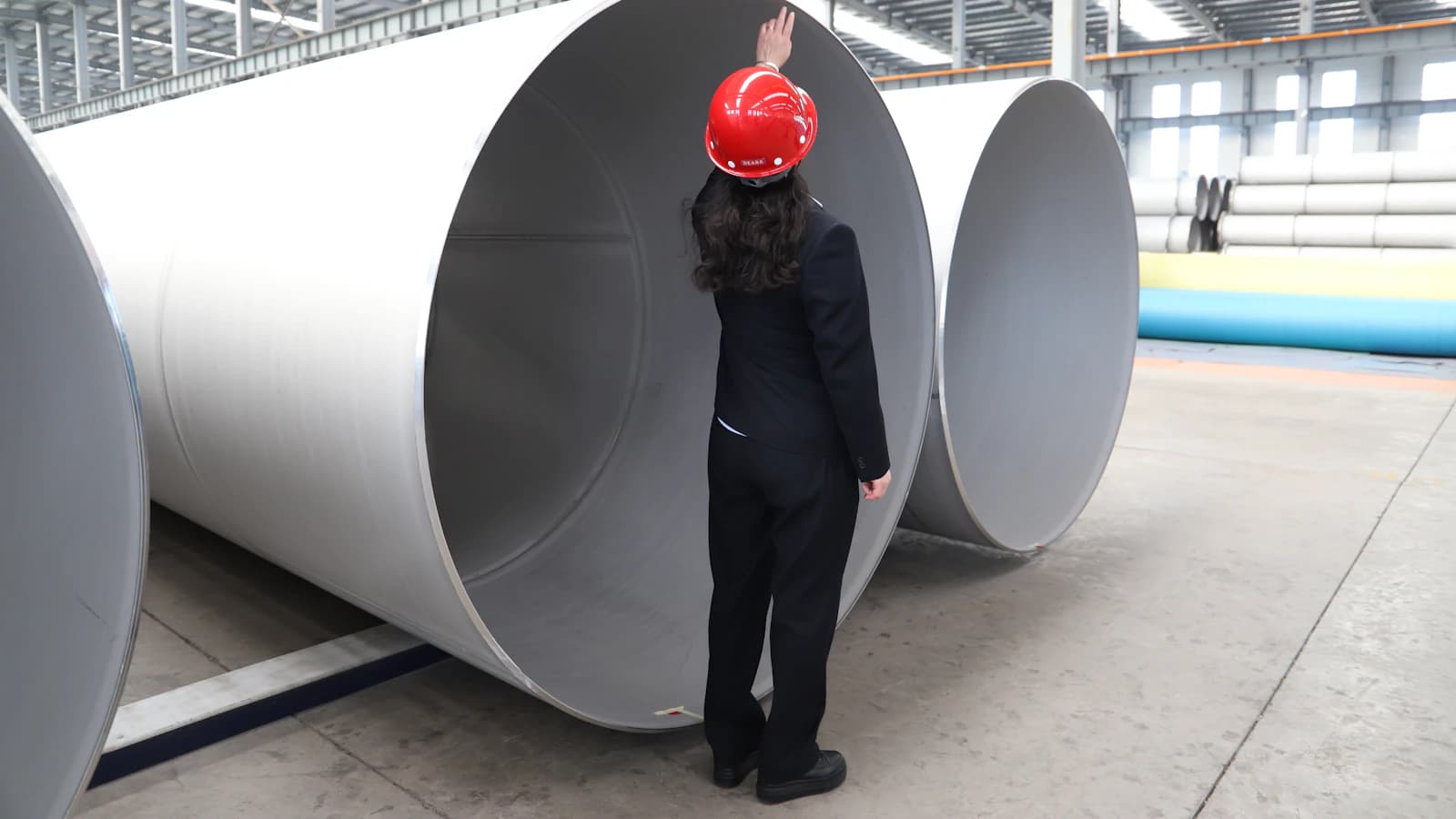 Especialista inspecciona grandes componentes metálicos dentro de una planta industrial.